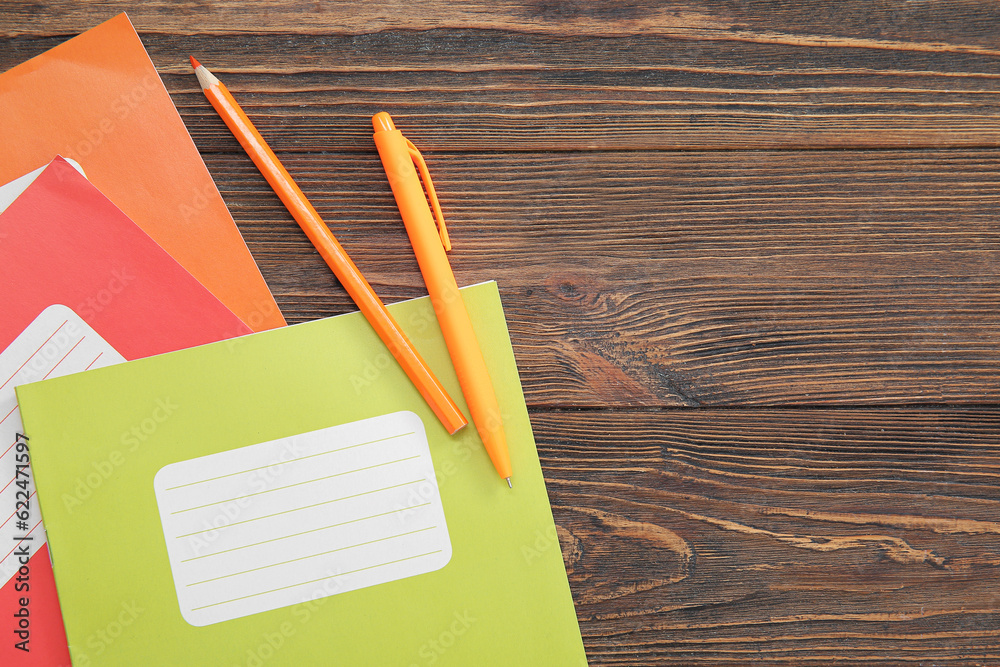 Different colorful notebooks with stationery on brown wooden background