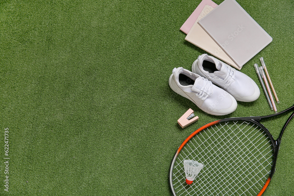 Sneakers with badminton shuttlecock, racket and different stationery on color background