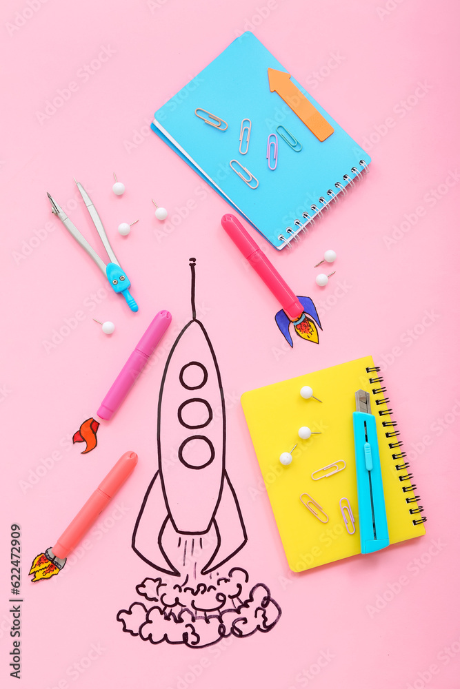 Creative composition with drawn rocket and different stationery on pink background