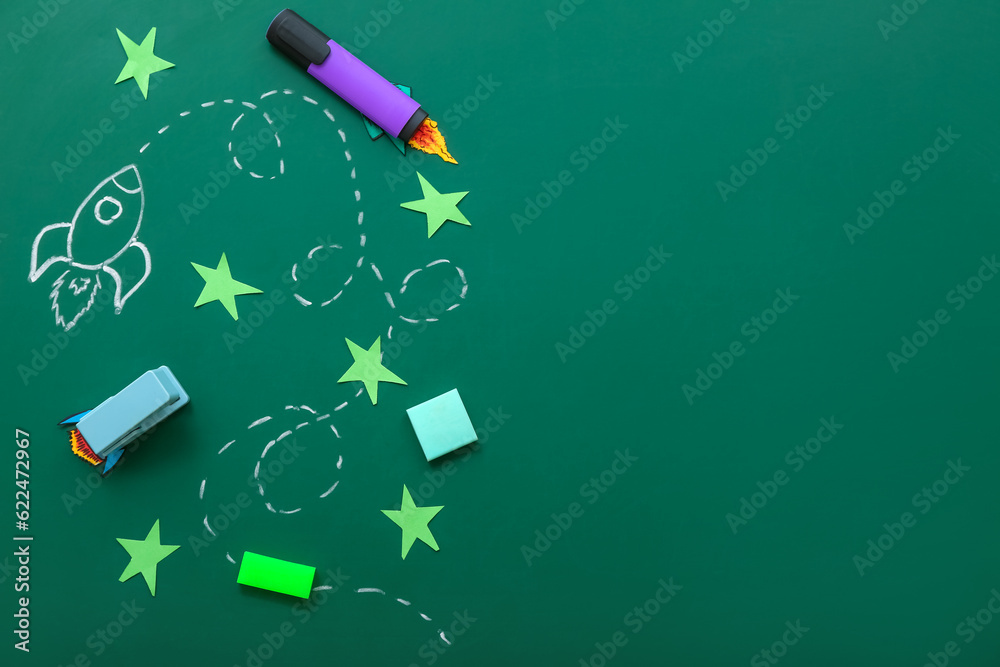 Creative composition with rockets, stars and different stationery on green chalkboard