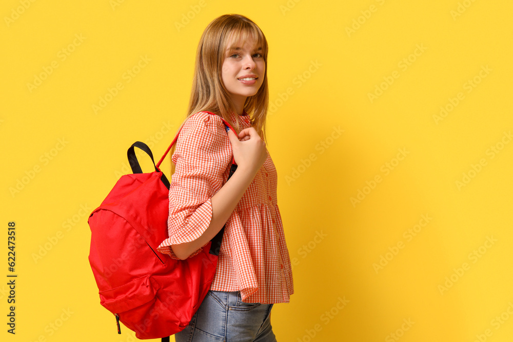 Female student with backpack on yellow background