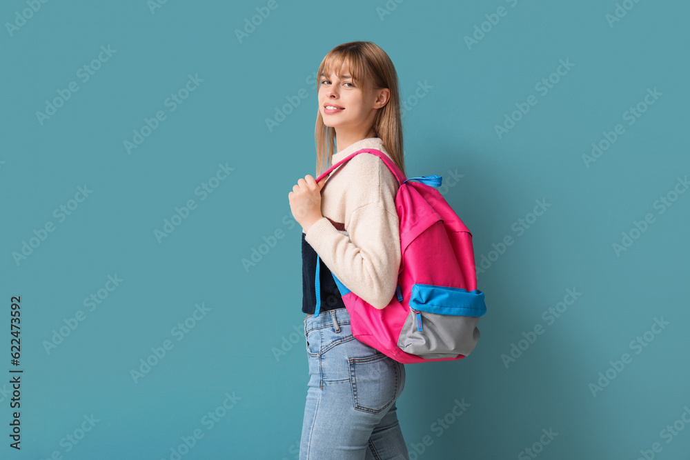 Female student with backpack on blue background