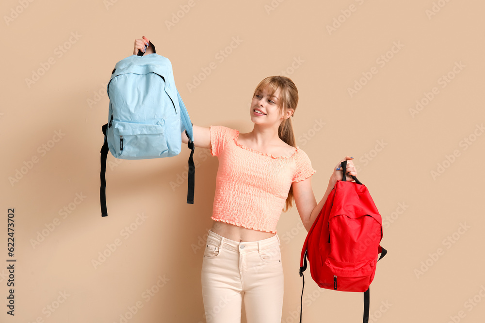 Female student with backpacks on beige background