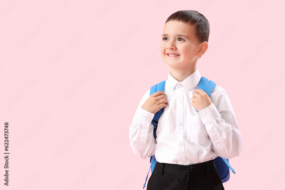 Little schoolboy with backpack on pink background