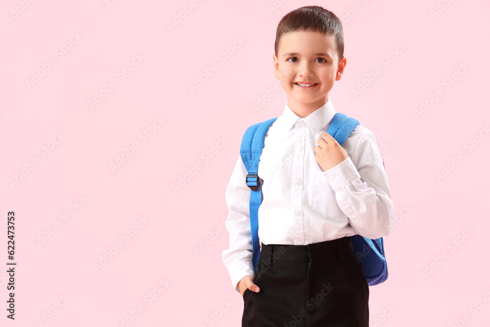 Little schoolboy with backpack on pink background