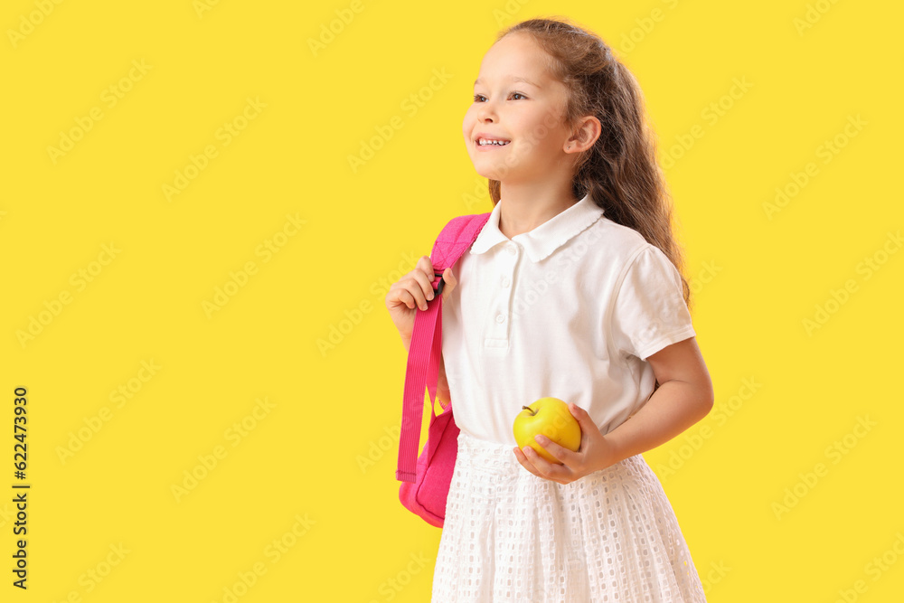 Little schoolgirl with apple on  yellow background