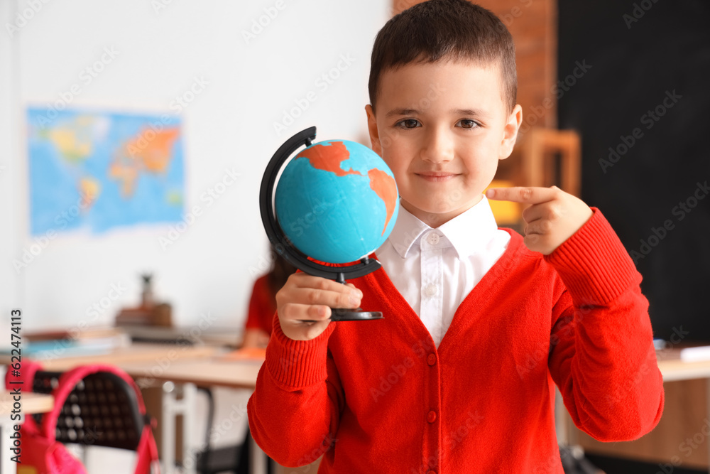 Little schoolboy with globe in classroom