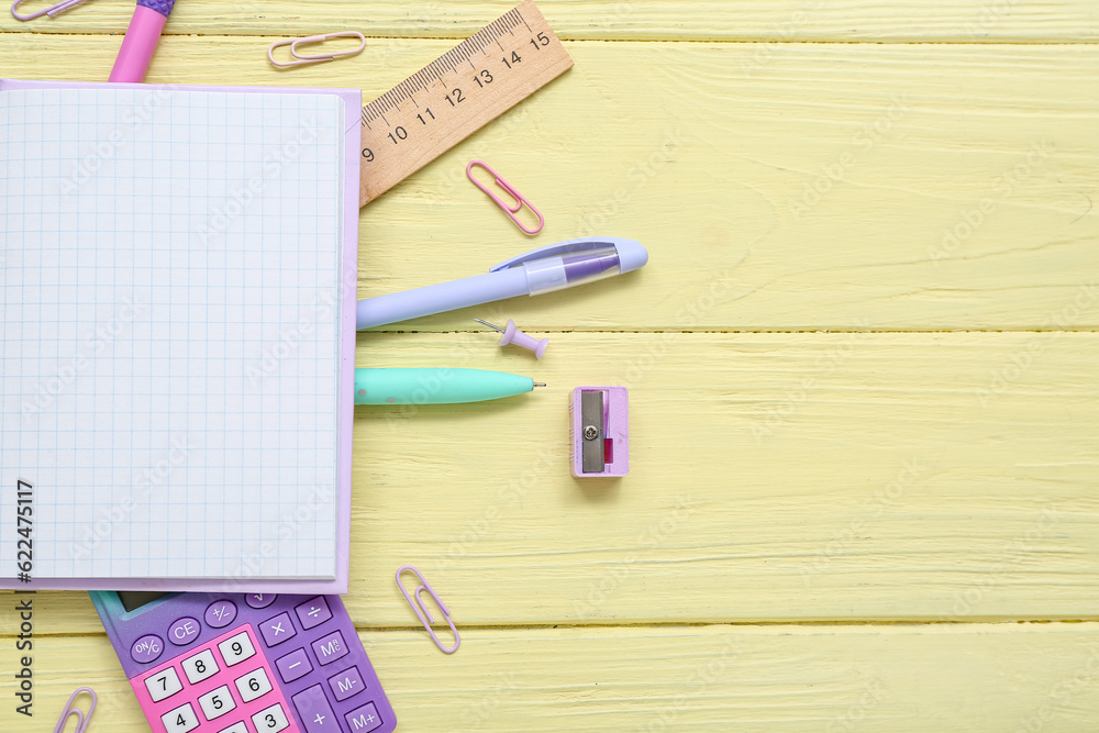 Blank notebook with different stationery and calculator on yellow wooden background