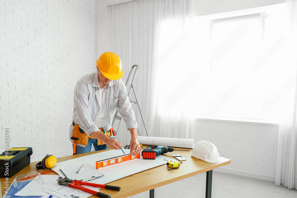 Mature builder working at table in room