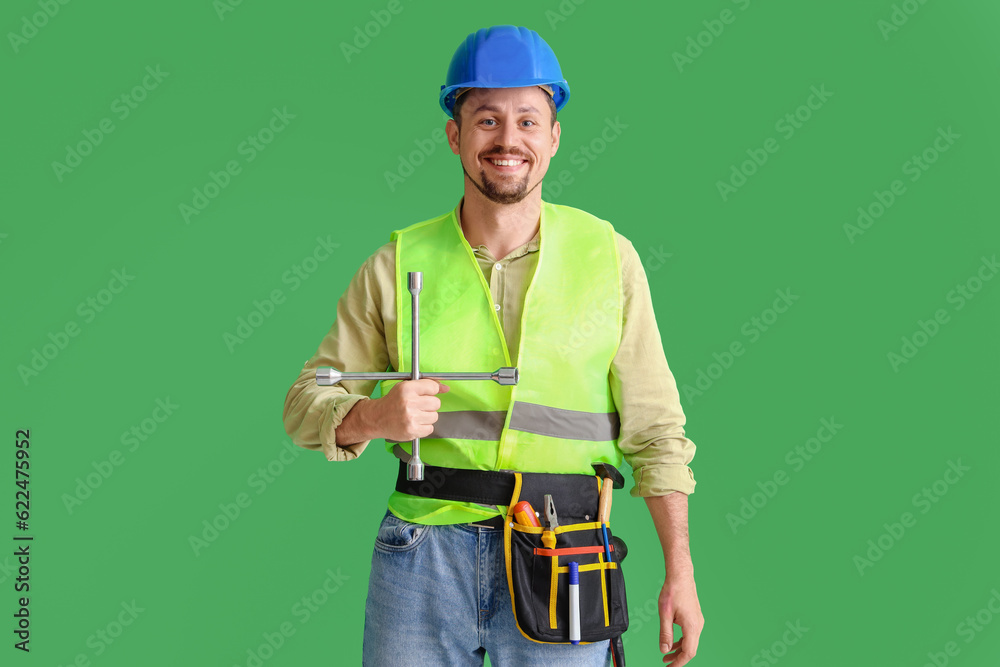 Male builder with tools on green background