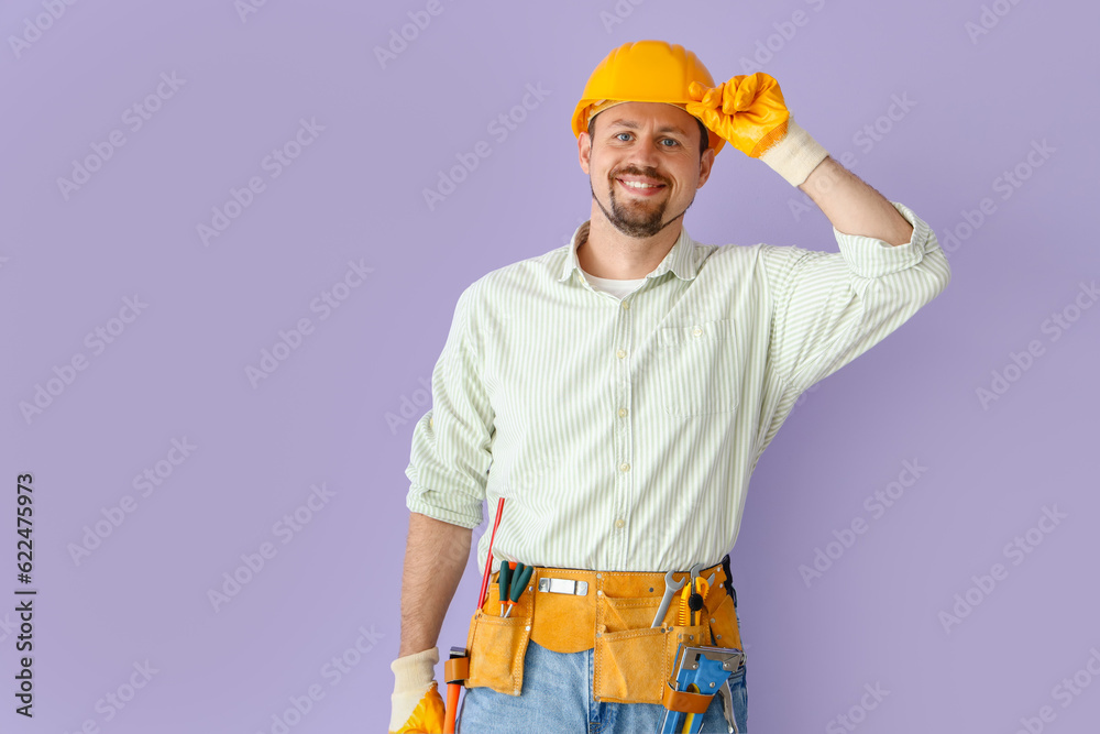 Male builder in hardhat on lilac background