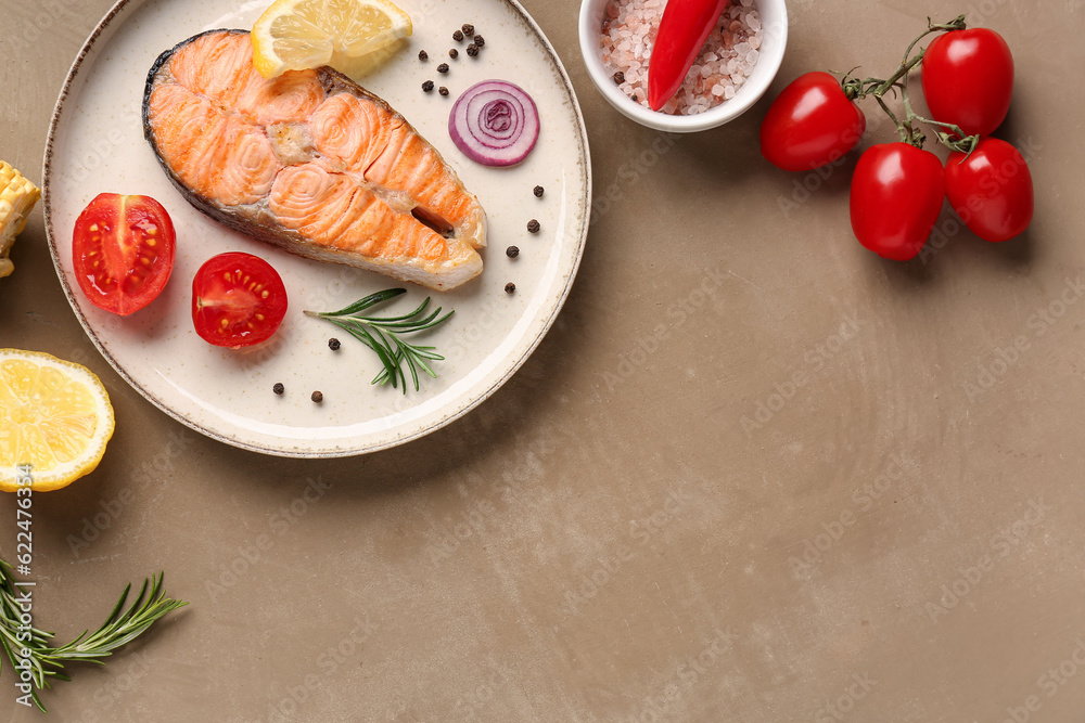 Plate with tasty grilled salmon steak and vegetables on beige background