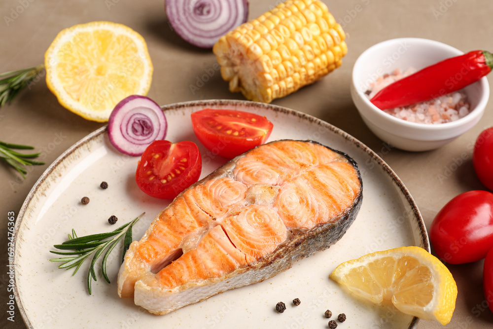 Plate with tasty grilled salmon steak and vegetables on beige background