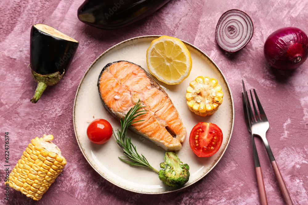 Plate with tasty grilled salmon steak, lemon and vegetables on purple background