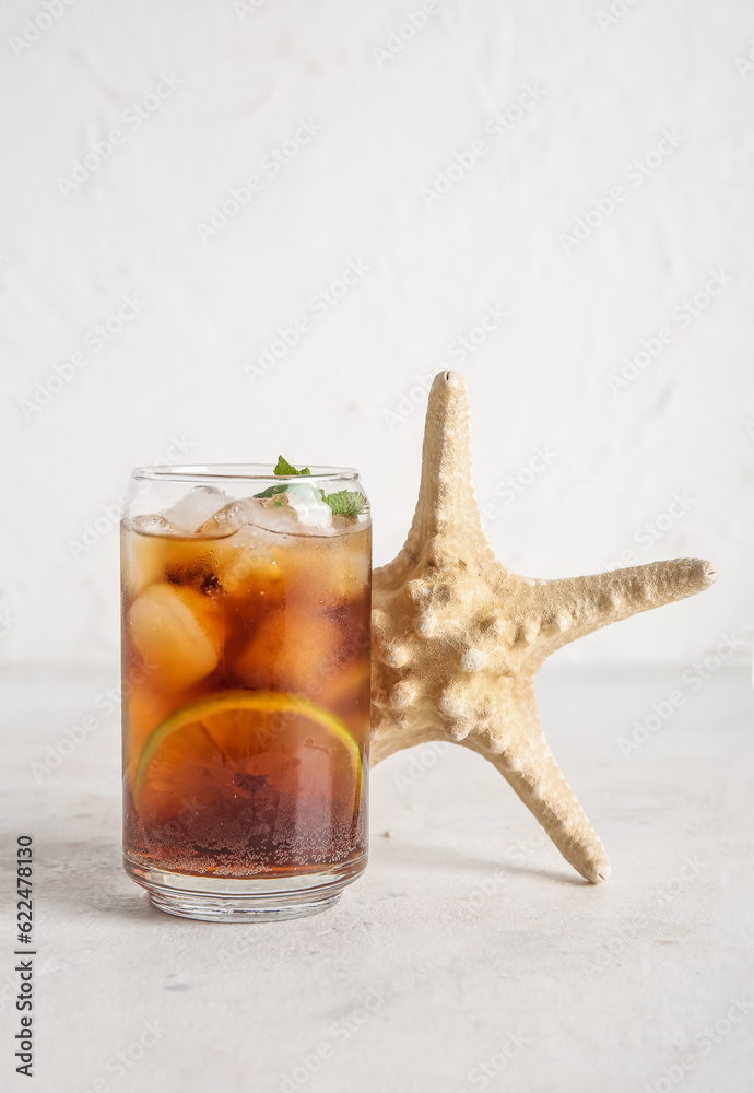 Glass of cold Cuba Libre cocktail and starfish on white background