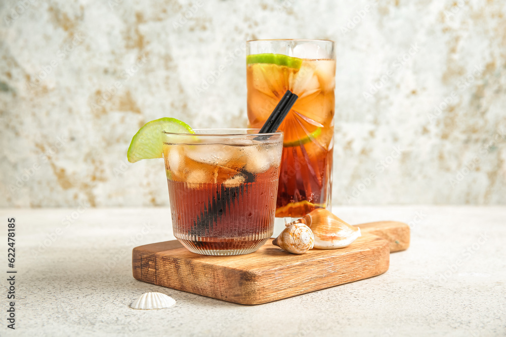 Board with glasses of cold Cuba Libre cocktail and seashells on white background