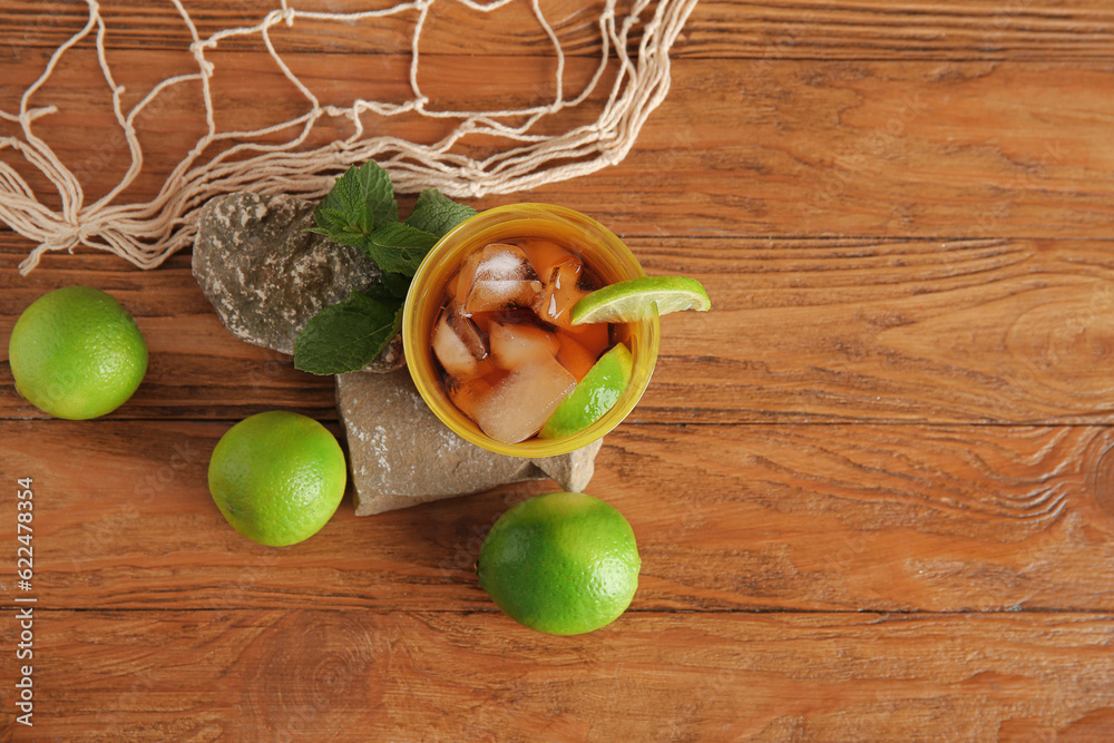 Stones with glass of cold Cuba Libre cocktail and net on wooden background