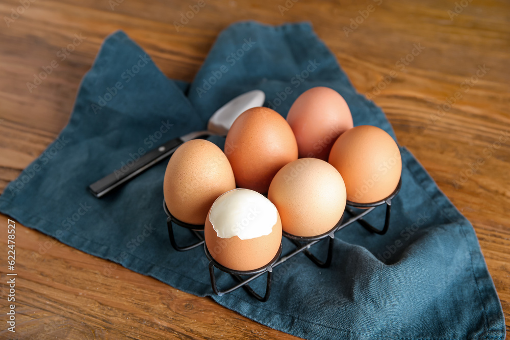 Holder with boiled chicken eggs on wooden background