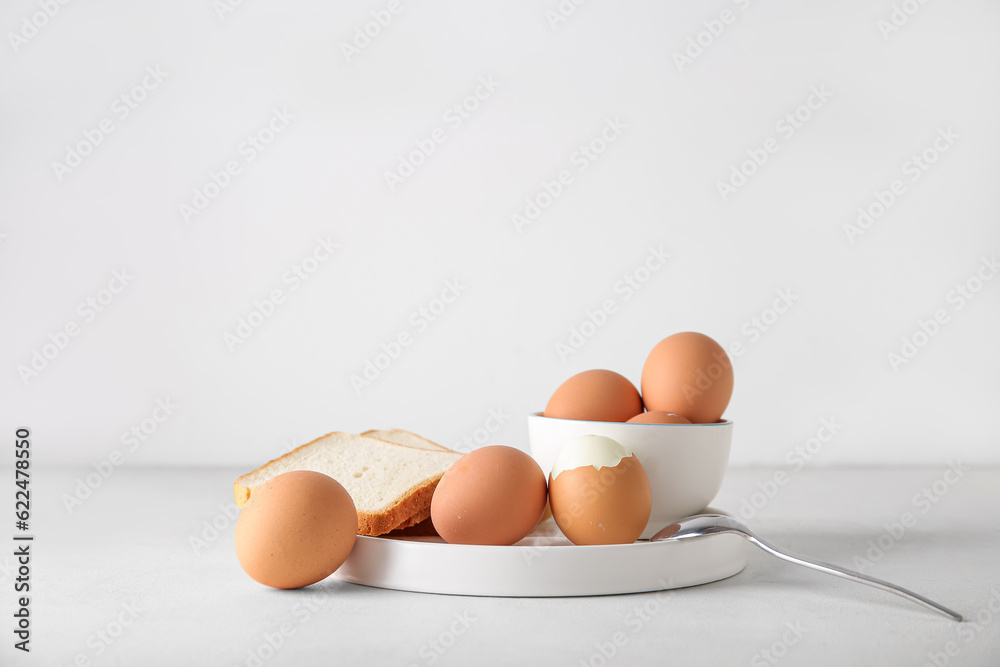 Plate and bowl with boiled chicken egg on white background