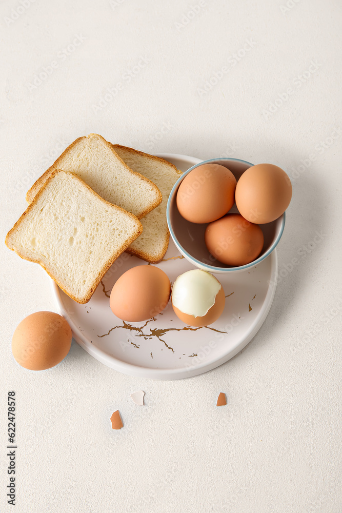 Plate and bowl with boiled chicken egg on white background