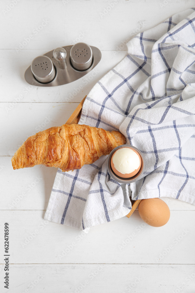 Holder with boiled chicken egg and croissant on white wooden background