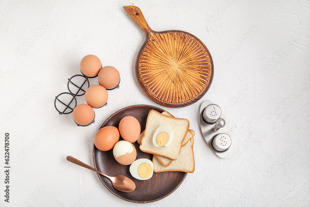 Plate and holder with boiled chicken eggs on white background