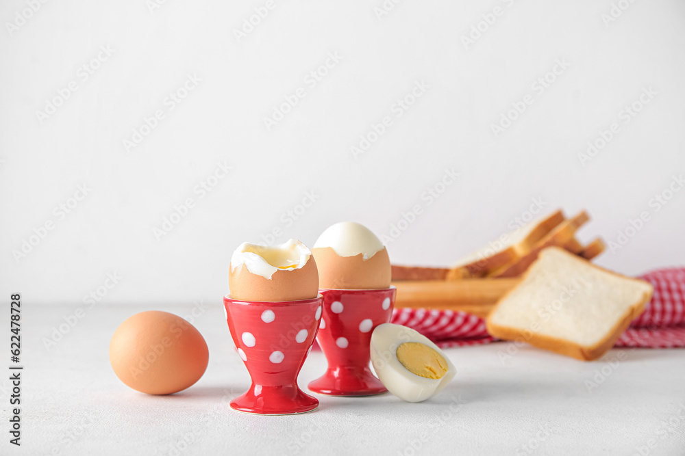 Holders with boiled chicken eggs on white background