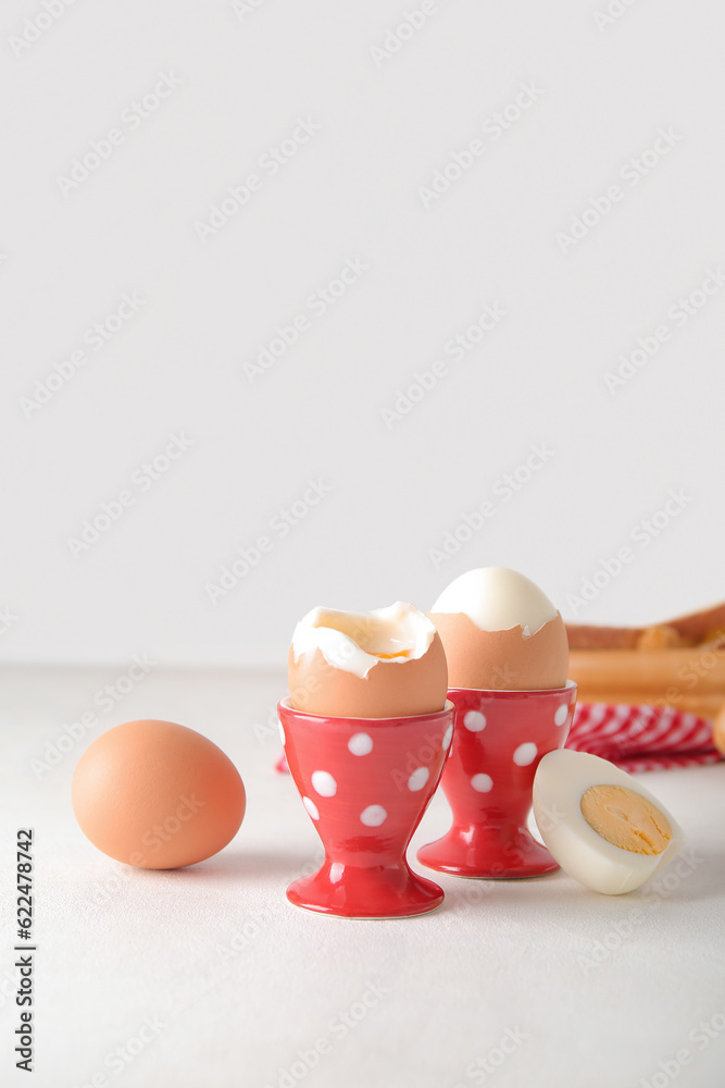 Holders with boiled chicken eggs on white background