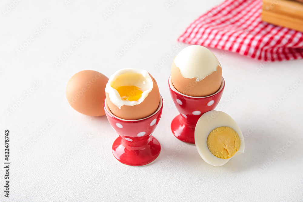 Holders with boiled chicken eggs on white background