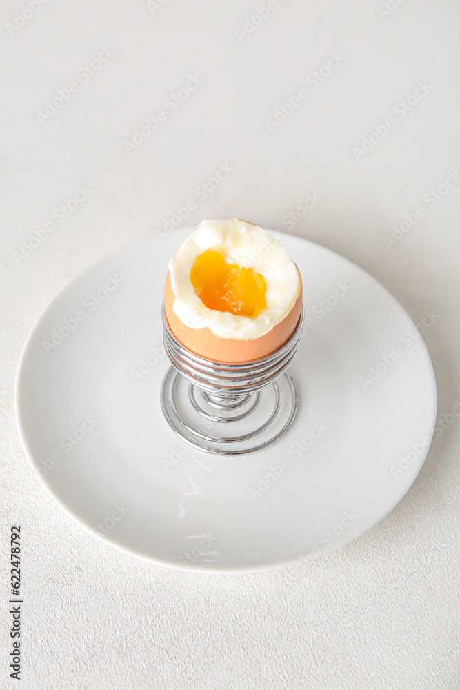 Holder with boiled chicken egg on white background