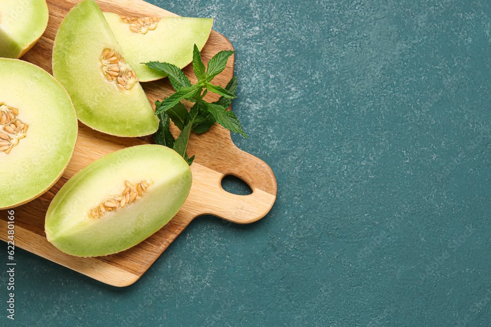 Board with pieces of sweet melon on blue background