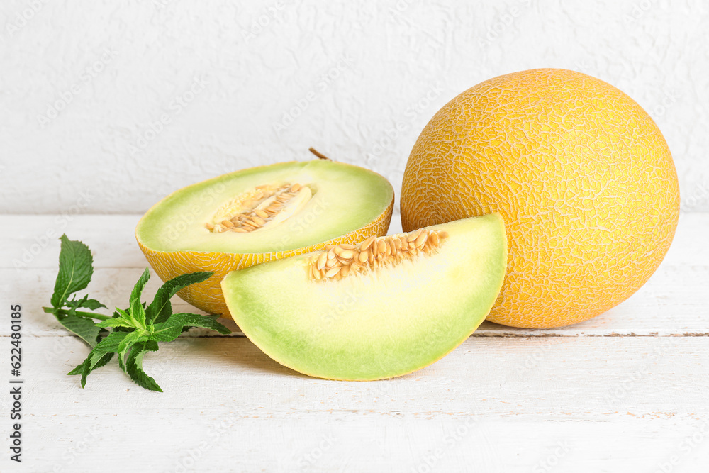 Sweet melon with pieces and mint on white wooden table