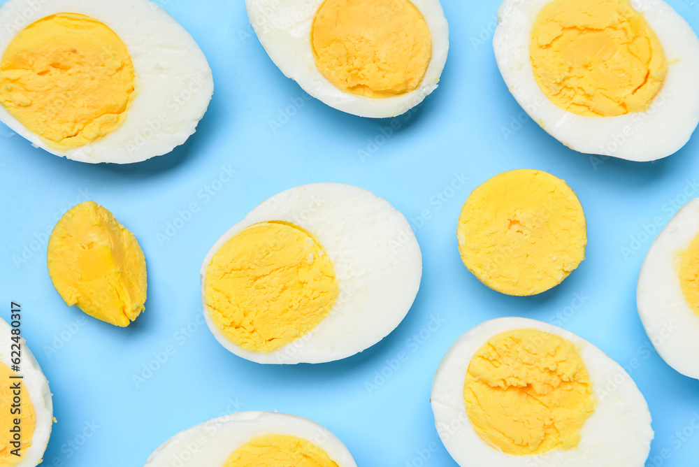 Halves of tasty boiled eggs on blue background