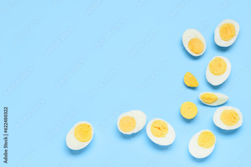 Halves of tasty boiled eggs with slice on blue background