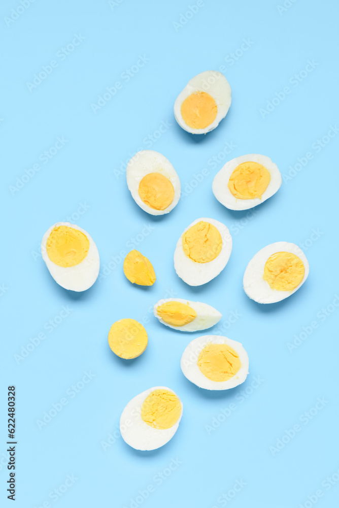 Halves of tasty boiled eggs with slice on blue background