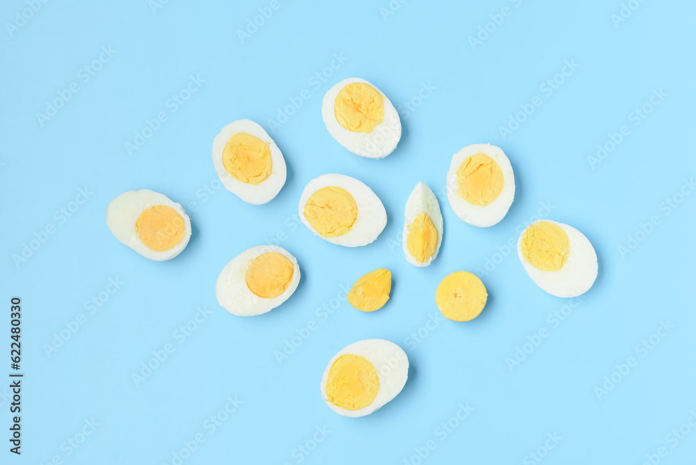 Halves of tasty boiled eggs with slice on blue background