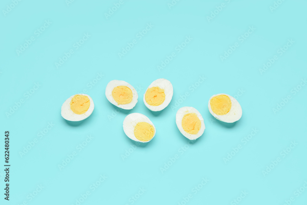 Halves of tasty boiled eggs on blue background