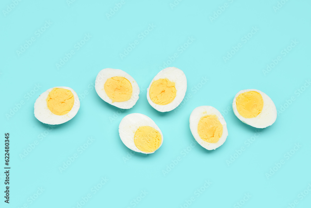 Halves of tasty boiled eggs on blue background