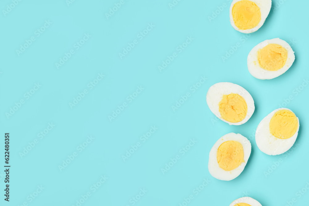 Halves of tasty boiled eggs on blue background