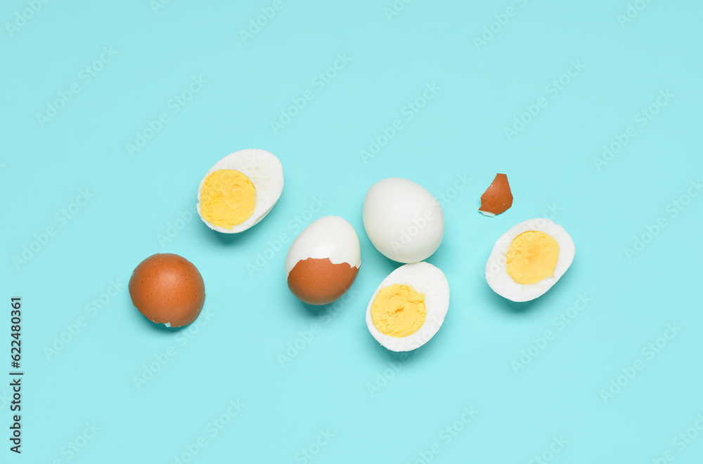 Tasty boiled eggs with halves and shells on blue background