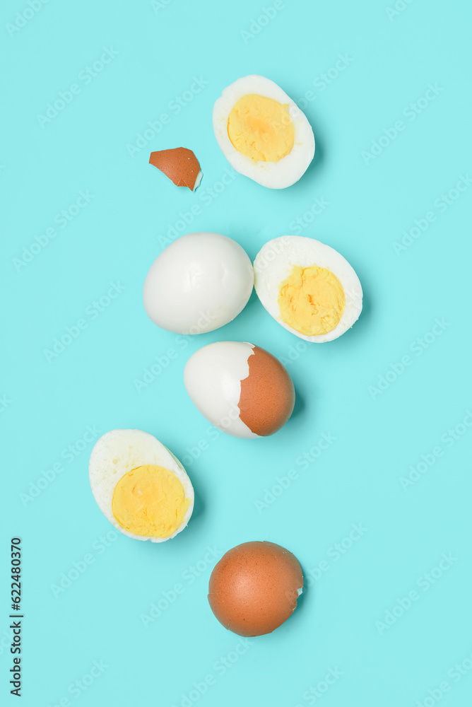 Tasty boiled eggs with halves and shells on blue background