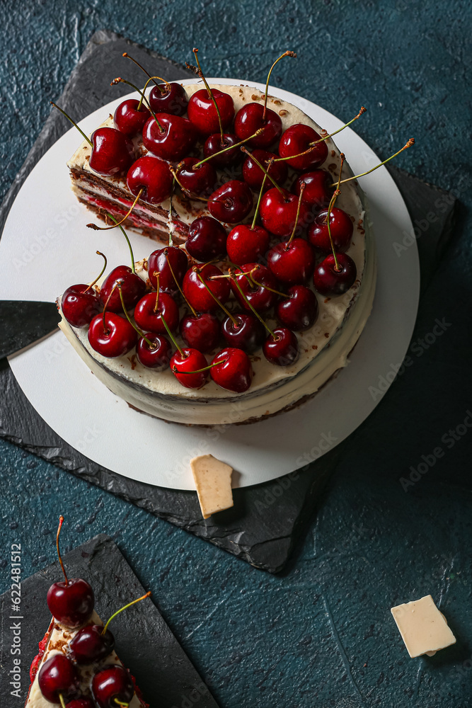 Boards with tasty cherry cake on blue background