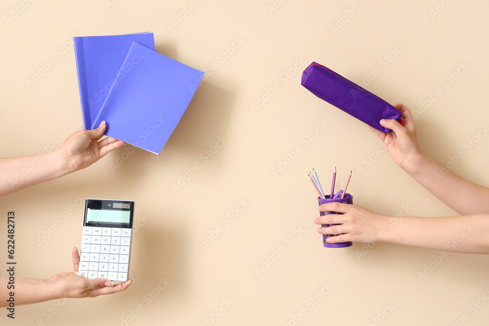 Female hands holding school supplies on beige background