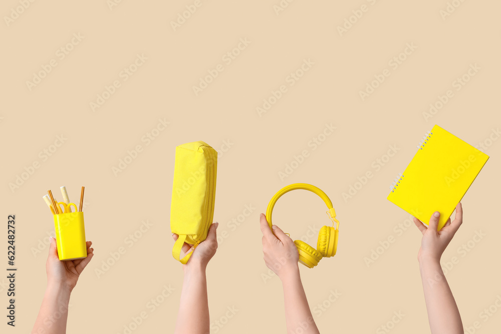 Female hands holding school supplies on beige background