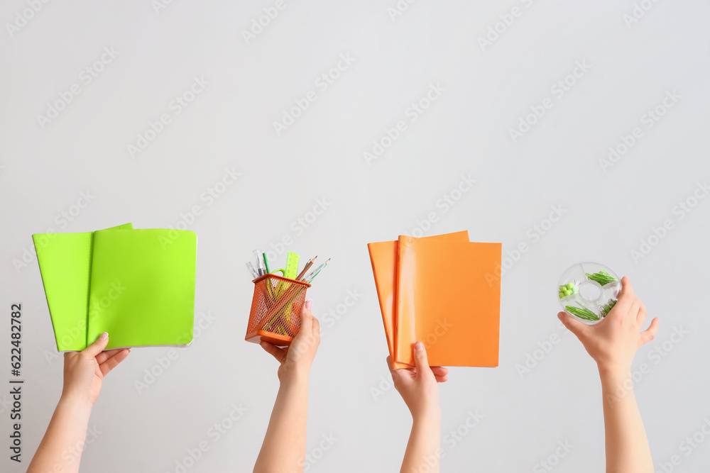 Female hands holding school supplies on grey background