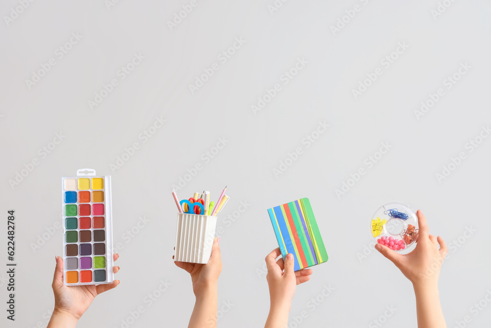 Female hands holding school supplies on grey background