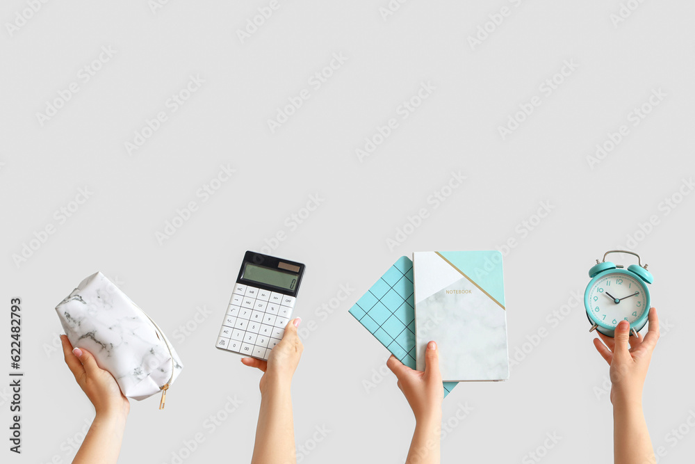 Female hands holding school supplies on grey background