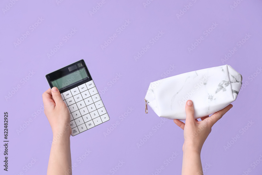 Female hands holding calculator and pencil case on lilac background