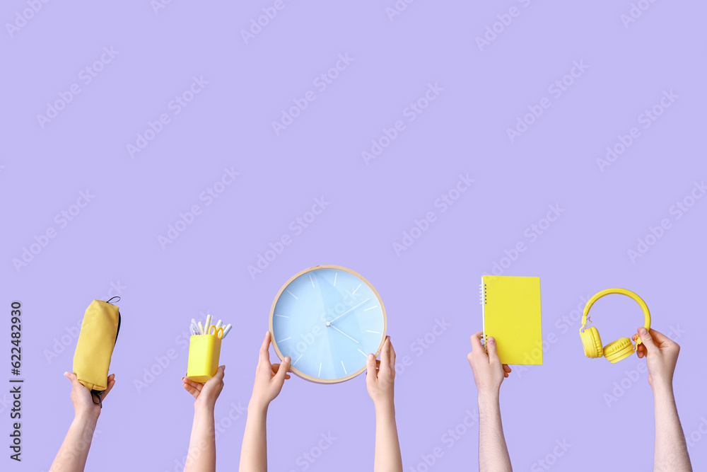 Many hands holding school supplies on lilac background