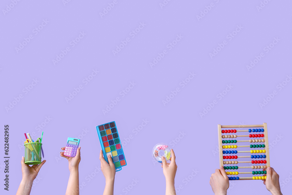 Many hands holding school supplies on lilac background